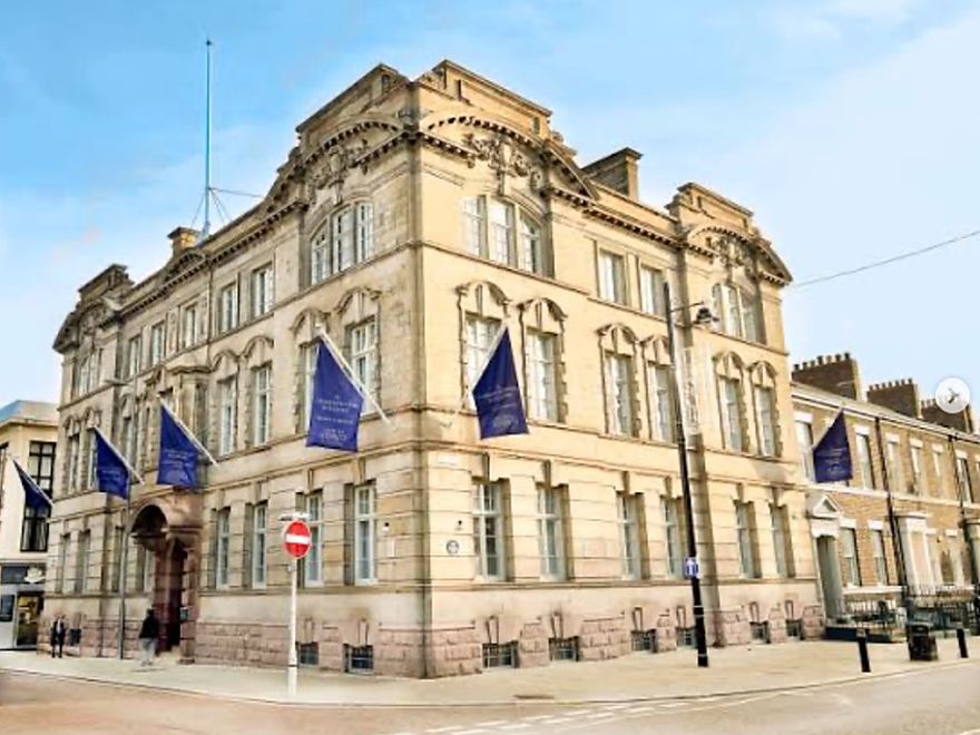 The Commissioners Building, a stone Victorian corner building on St. Thomas Street in Sunniside, Sunderland, flying navy banners.