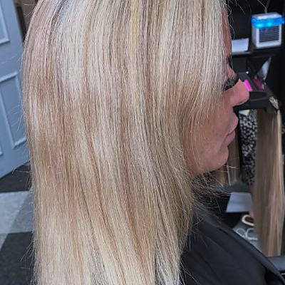 A blonde client's own hair before extensions, shown from the side.